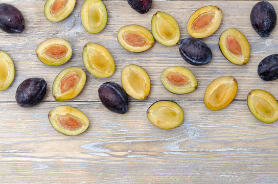 Zwetschgen ganz und halbiert auf Holzhintergrund