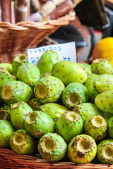 Green opuntia fruits on a local market in Funchal, Madeira, Portugal. Prickly pear or Indian figs. Exotic fruits are grown on cactus. TRANSLATION OF THE SIGN: Tabaibos - opuntia fruits in Portuguese