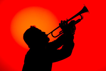 Silhouette of a jazz musician  playing trumpet, isolated in red background. Jazz music concept.