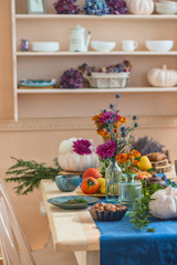 Pumpkins, flowers, tea and autumn paraphernalia on the festively served autumn table  