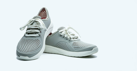 A pair of grey shoes on white background. Comfortable shoes with pore. Breathable rubber shoes....