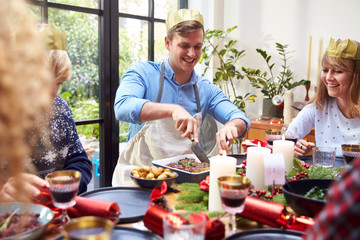 Group Of Friends Sitting Around Dining Table At Home As Vegetarian Christmas Dinner Is Served