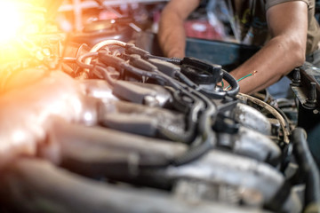 hands of mechanic repairing the car's engine close up, photo with illumination, light