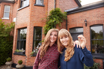 Portrait Of Excited Gay Female Couple Standing Outside New Home Holding Keys Together