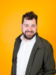 one cool man with black beard and black hair is posing in front of orange background