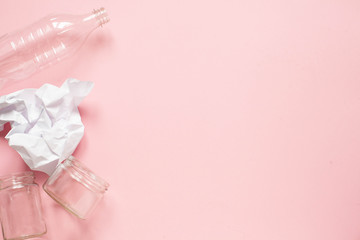 zero pollution and eco-friendly lifestyle acute social problems. plastic bottle, crumpled paper and two glass jars on a pink background copy space