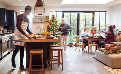 Group Of Friends At Home Preparing And Serving Christmas Dinner