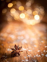 Weihnachtlicher Sternanis mit Licher Bokeh auf einem braunen Holztisch, Advent