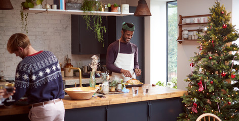 Gay Male Couple At Home In Kitchen Cooking Dinner On Christmas Day Together
