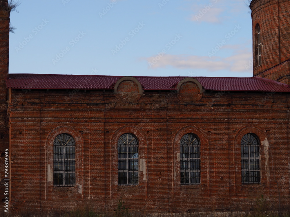 Wall mural old brick wall with towers, arched windows and iron bars background of blue sky. ancient building cl