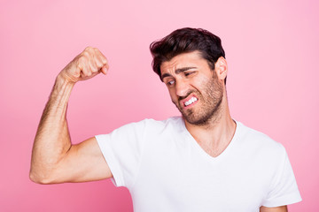 Portrait of funny funky disappointed middle eastern man show his muscles look dislike new sportive gym fitness body building workout wear white t-shirt isolated over pastel color background