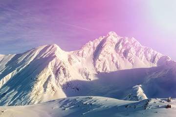Dramatic scenic pink to purple sunrise in austrian alpine mountain peaks covered with snow layer in winter . Idyllic clear sky on background. Natural rocky Tyrol landscape