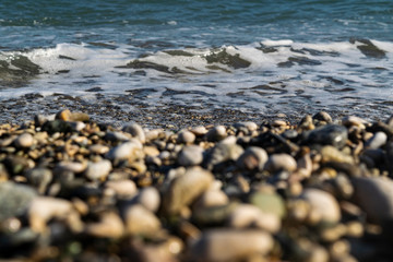 Sea wave on a pebble beach, foreground out of focus.