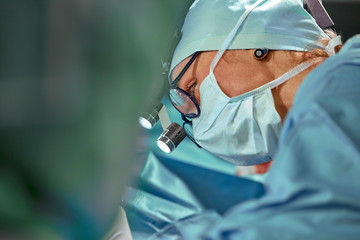 Close up portrait of female surgeon doctor wearing protective mask and hat during the operation....