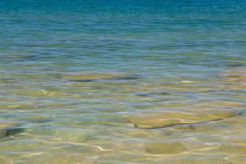 Clear water texture in blue and orange. Background of the ocean and the sea backlit by the sun. Soft waves. Natural water