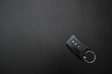 Remote controlled car key on the black wooden background, top view.