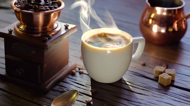 Coffee cup with freshly brewed coffee on an old vintage table. Steam rises from the cup.