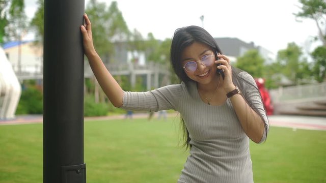 Happy Young Asian woman in glasses is talking on phone. Slow motion
