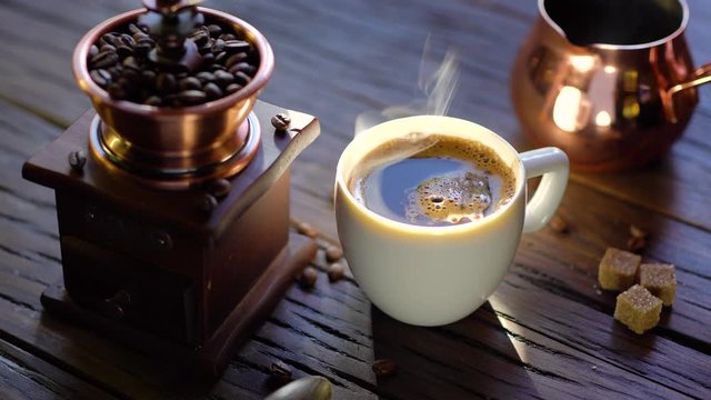 Coffee cup with freshly brewed coffee on an old vintage table. Steam rises from the cup.