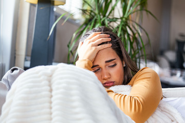 Sick woman with headache sitting under the blanket. Sick woman with seasonal infections, flu,...