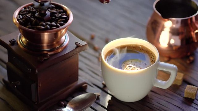 Coffee cup with freshly brewed coffee on an old vintage table. Steam rises from the cup.