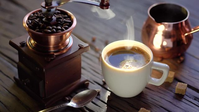 Coffee cup with freshly brewed coffee on an old vintage table. Steam rises from the cup.