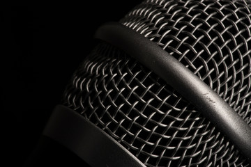 Close-up black microphone head isolated on black background.
