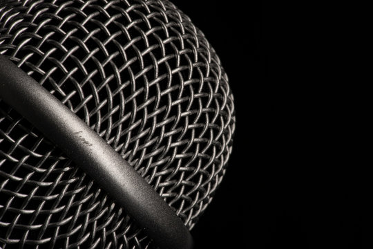 Close-up black microphone head isolated on black background.