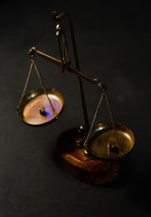 Old gojd scales for weighing little things. Symbol of law and scales of justice on black table. Antique libra with weights in room with vintage interior. Top view