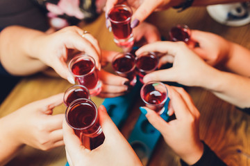 Close up shot of group of people clinking glasses with wine or champagne in front of bokeh...