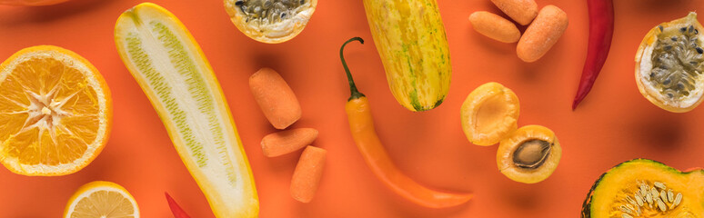 top view of yellow fruits and vegetables on orange background, panoramic shot