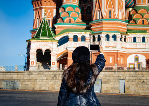 Back view of young woman she's take a picture by smartphone at Moscow,Russia,Red square,view of St. Basil's Cathedral