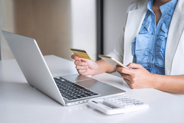 Young woman consumer holding smartphone, credit card and typing on laptop for online shopping and payment make a purchase on the Internet, Online payment, networking and buy product technology