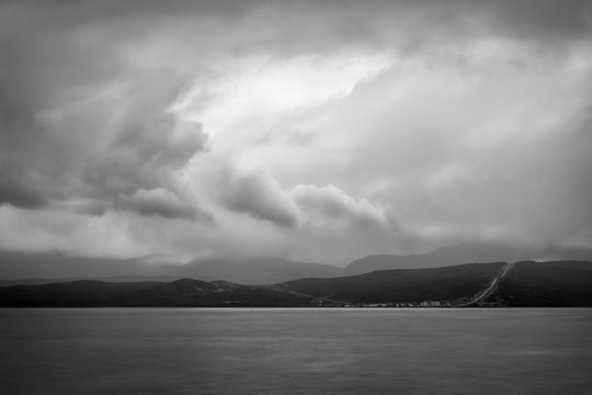 Overcast weather seascape in black and white - Coastline view from a ferry boat towards Prony Bay in New Caledonia in French Polynesia in South Pacific ocean.