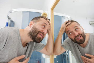 Worried man looking at his decreasing hairline