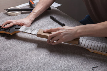 the master polishes the frets on the fretboard of the guitar.
