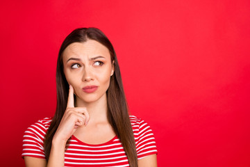 Close up photo of charming attractive thinking girl wearing red striped t-shirt pondering over something puzzling while isolated over red background