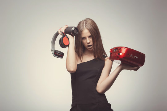 Joyable attractive fashion pretty girl listening music with headphones, speaker, record player, holding thm in hands and wearing red gloves, take pleasure with song. Lifestyle woman concept