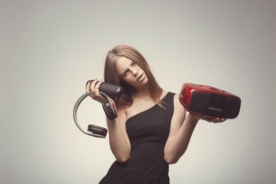 Joyable attractive fashion pretty girl listening music with headphones, speaker, record player, holding thm in hands and wearing red gloves, take pleasure with song. Lifestyle woman concept