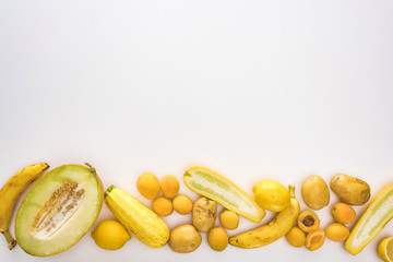 top view of yellow fruits and vegetables on white background with copy space