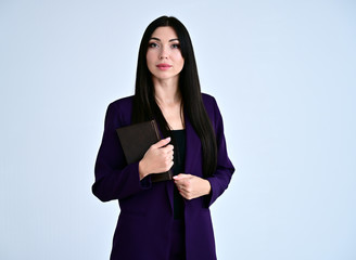 Portrait of a pretty brunette girl with good makeup with long hair on a white background in a business suit with a folder in her hands. Stands in different poses with emotions.
