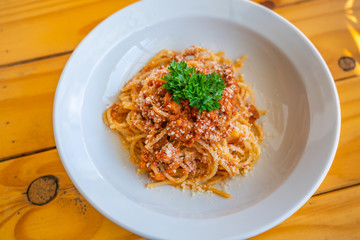 Tasty minced beef spaghetti decorated with parsley on white plate