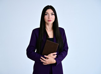 Obraz premium Portrait of a pretty brunette girl with good makeup with long hair on a white background in a business suit with a folder in her hands. Stands in different poses with emotions.