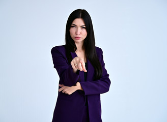 Portrait of a pretty brunette girl with good makeup with long hair on a white background in a dark business suit. Stands in different poses with emotions.