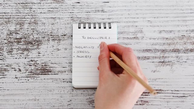 hand ticking off negativity stress and anxiety as elements to declutter from life
