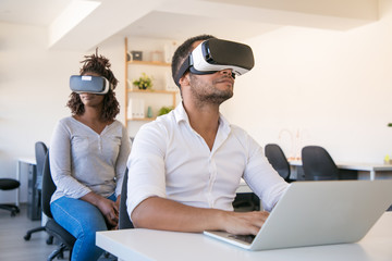 Multiethnic colleagues wearing VR goggles enjoying experience. Man and woman in virtual reality...
