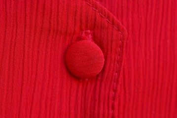 red fabric texture with a large single button on clothes