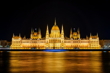 Fototapeta premium Illuminated historical building of Hungarian Parliament at night on Danube River Embankment