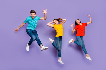Full length size body photo of two beautiful carefree cheerful excited ladies and one comic funny in blue t-shirt guy waving hand saying hello isolated violet background
