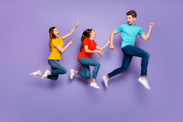 Fototapeta na wymiar Full size body side profile view photo of one unhappy shocked guy running away from two obsessive addicted ladies isolated violet background